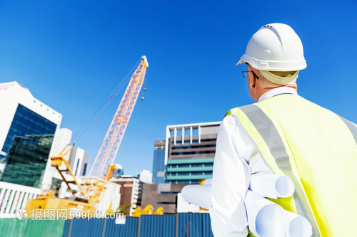 建筑工地的工程师建设者工程师建筑工人施工场景穿着带蓝图的安全背心